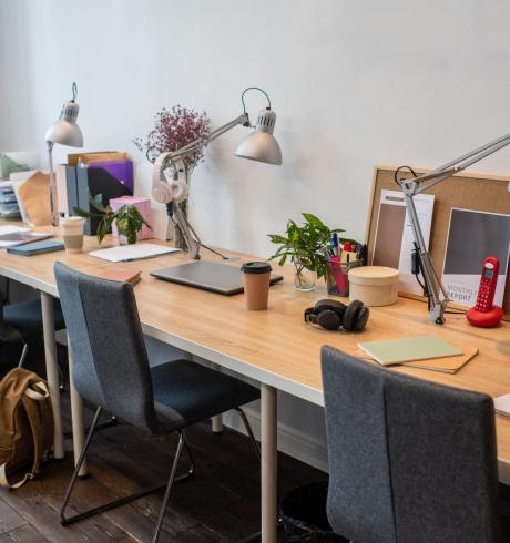 Part of classroom or office with several desks and chairs with supplies standing along wall